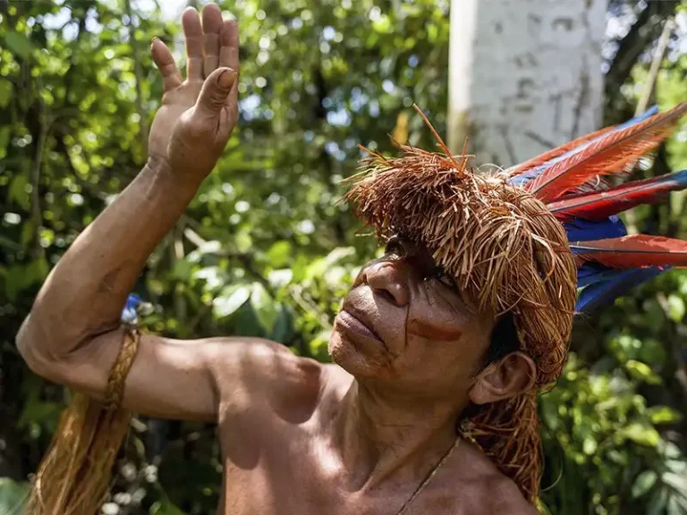 Hombre de una comunidad indígena del Amazonas peruano con tocado tradicional en la selva, representando la experiencia cultural del itinerario.