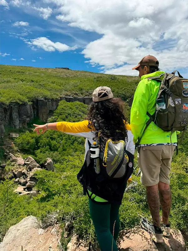 Guía de turismo de Vivak Aventuras señalando el paisaje a una turista durante una excursión de trekking en Caviahue.