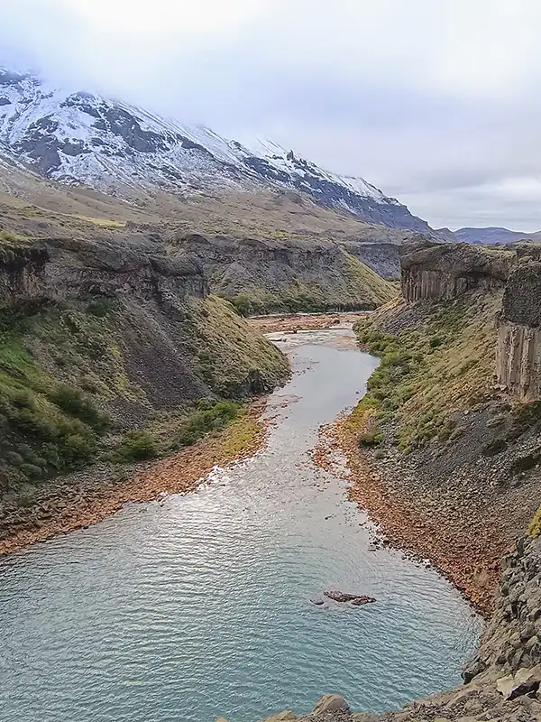 Vista panorámica del río Agrio serpenteando entre cañones hacia el Salto del Agrio, con montañas nevadas de Caviahue y Copahue al fondo. Excursión organizada por Vivak Aventuras.