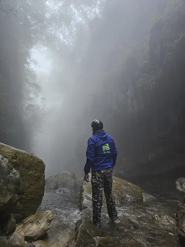 Persona explorando un cañón en las Yungas de Jujuy, rodeada de vegetación y niebla.