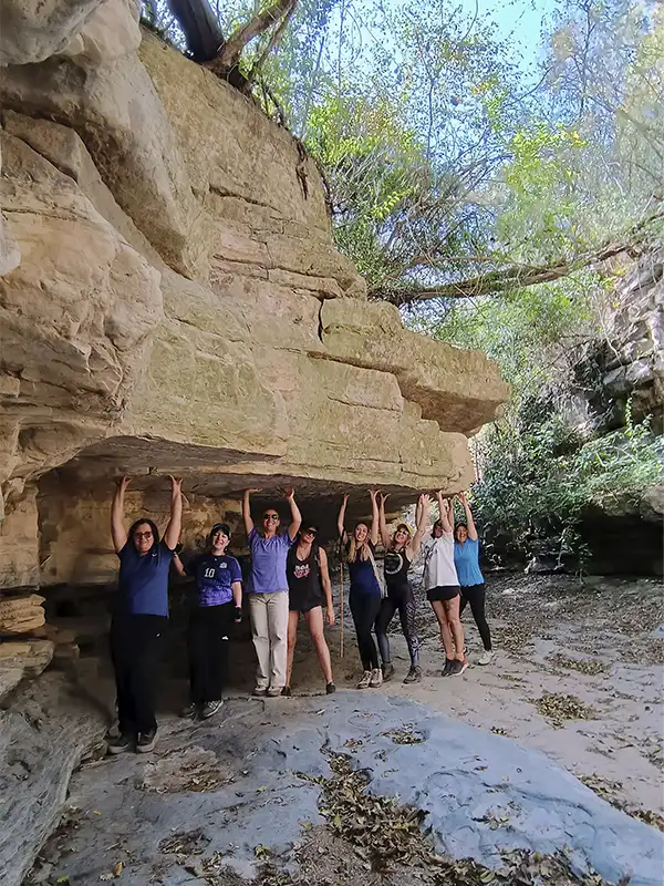Grupo de viajeros durante una excursión en las Yungas de Jujuy junto a una formación rocosa.
