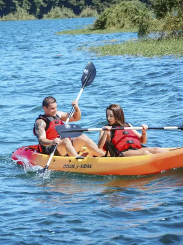 Pareja remando en kayak por las aguas azules del Lago Arenal rodeado de naturaleza tropical en Costa Rica