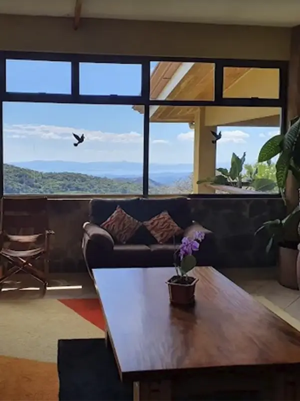 Acogedora sala de estar en el Hotel Montaña Monteverde con grandes ventanales que ofrecen vistas panorámicas al Golfo de Nicoya.
