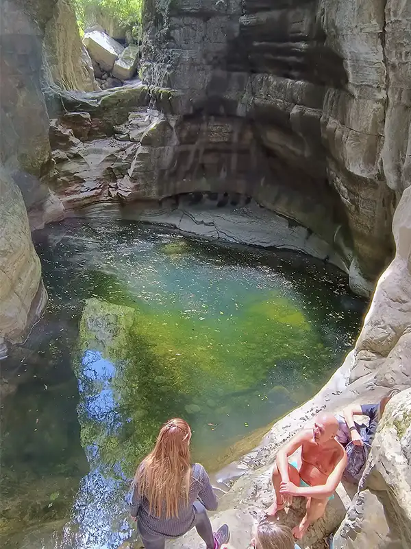 Viajeros disfrutando una poza natural de agua en las Yungas de Jujuy.