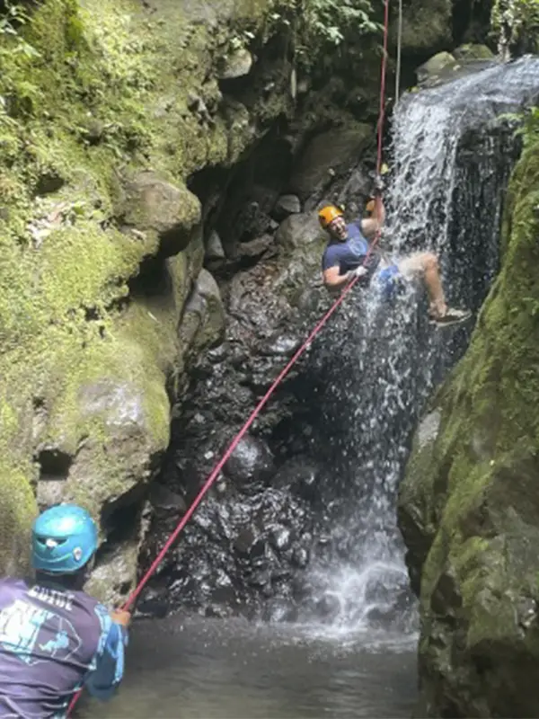 Viajero haciendo rappel en una catarata entre rocas cubiertas de musgo en Arenal, Costa Rica con Vivak Aventuras