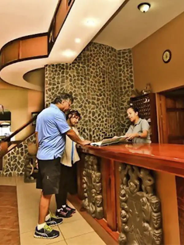 Huéspedes realizando el check-in en la cálida recepción de madera y piedra del Hotel Montaña Monteverde.