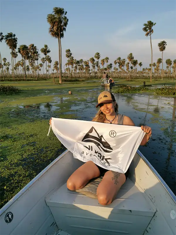 Viajera sosteniendo la bandera de Vivak Aventuras desde una canoa en los canales del Bañado La Estrella, Formosa — el tercer humedal más grande del mundo.