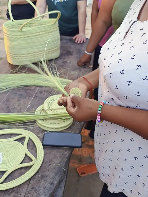Mujer de la comunidad pilagá tejiendo cestería artesanal en hoja de palma carandillo, técnica ancestral transmitida de generación en generación en el Bañado La Estrella, Formosa.