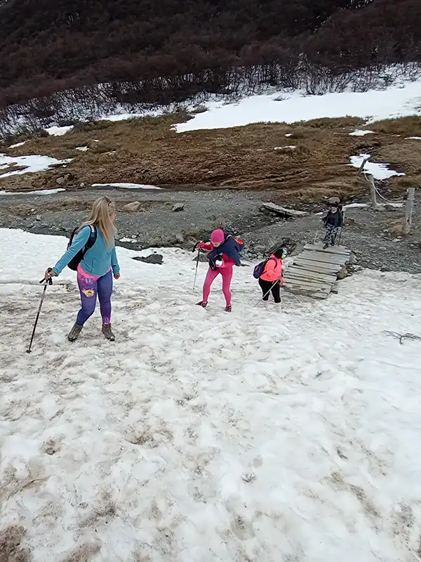 Grupo de mujeres haciendo trekking sobre nieve con bastones camino al Glaciar Martial, Ushuaia, Tierra del Fuego.