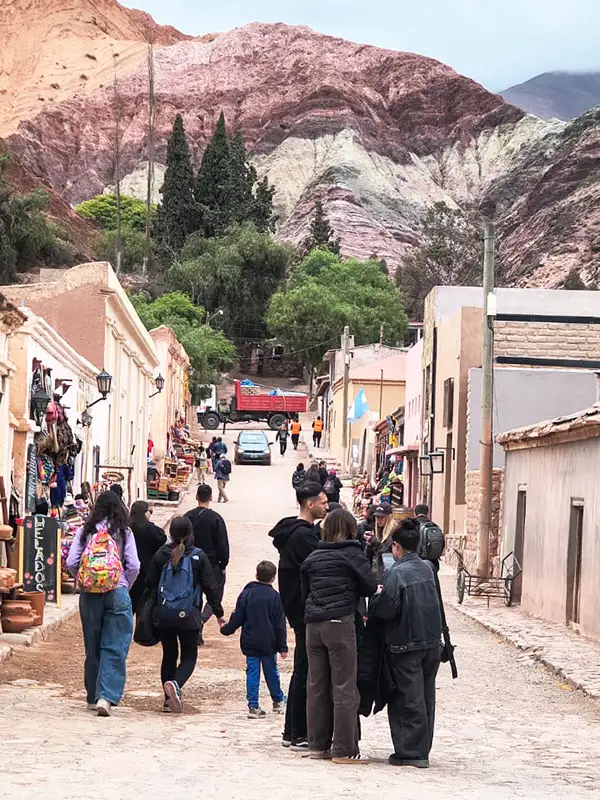 Grupo de viajeros recorriendo las calles de Purmamarca con el Cerro de los Siete Colores de fondo