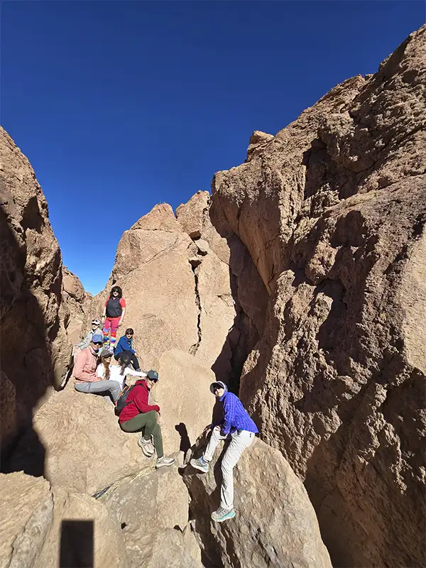 Grupo de personas explorando el interior del Cañón del Volcán Lincabur entre paredes de roca y cielo azul intenso