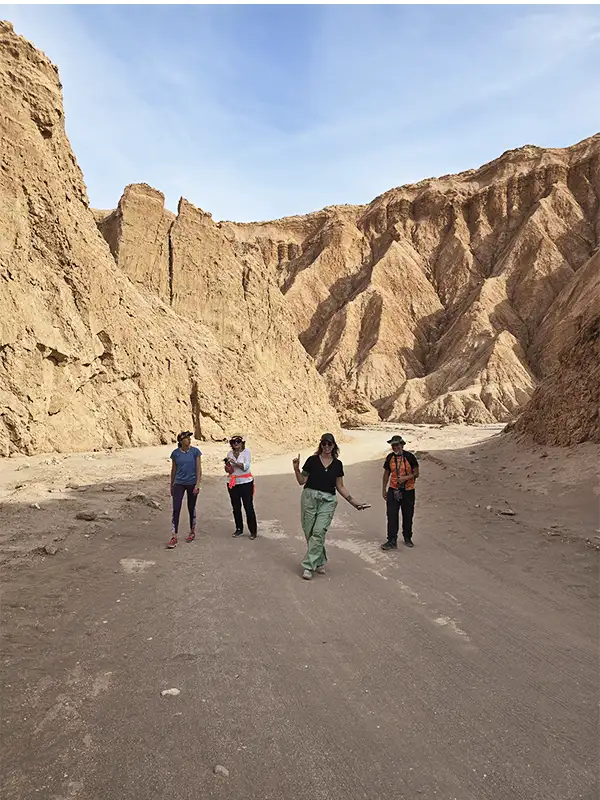 Grupo de viajeros recorriendo la antigua Ruta de la Muerte rodeados de paredes ocres en el desierto