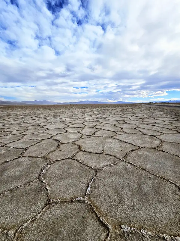 Superficie agrietada del Salar de Atacama con sus características formas hexagonales y cielo nublado al horizonte