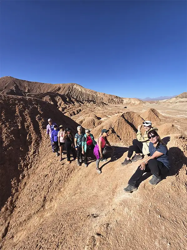 Grupo de viajeros caminando en fila sobre las formaciones rocosas del Valle de la Luna en el Desierto de Atacama