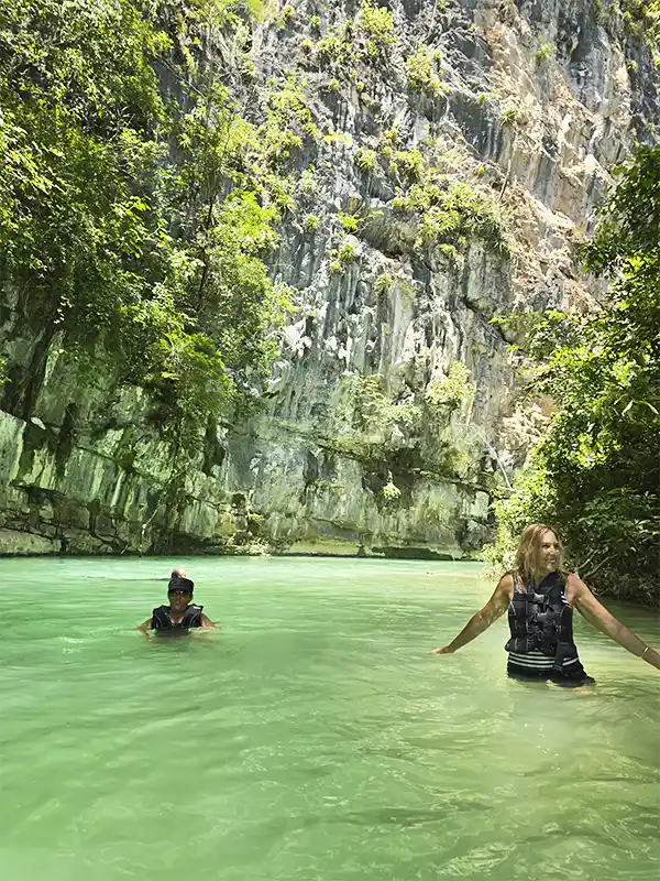Dos personas haciendo aquatrekking entre paredones rocosos en un cañón de Bonito
