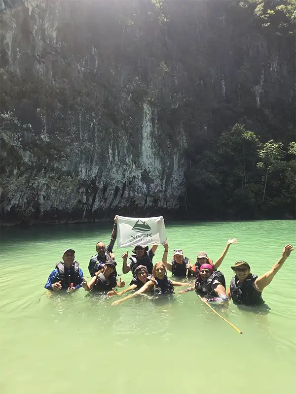 Grupo de viajeros con bandera de Vivak Aventuras haciendo aquatrekking en los Cânions do Salobra, Bonito
