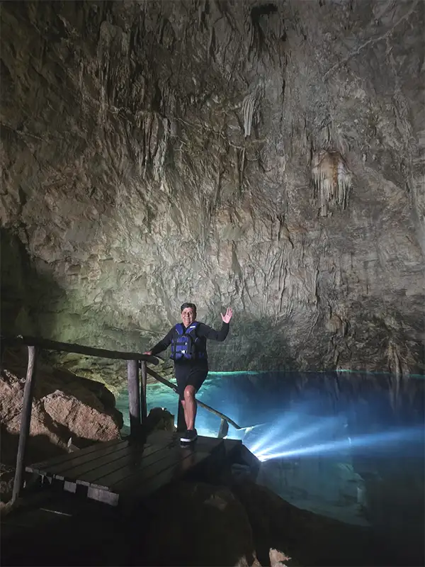 Estalactitas y formaciones rocosas iluminadas en el interior de la caverna, antes de bajar a flotar en sus aguas cristalinas.