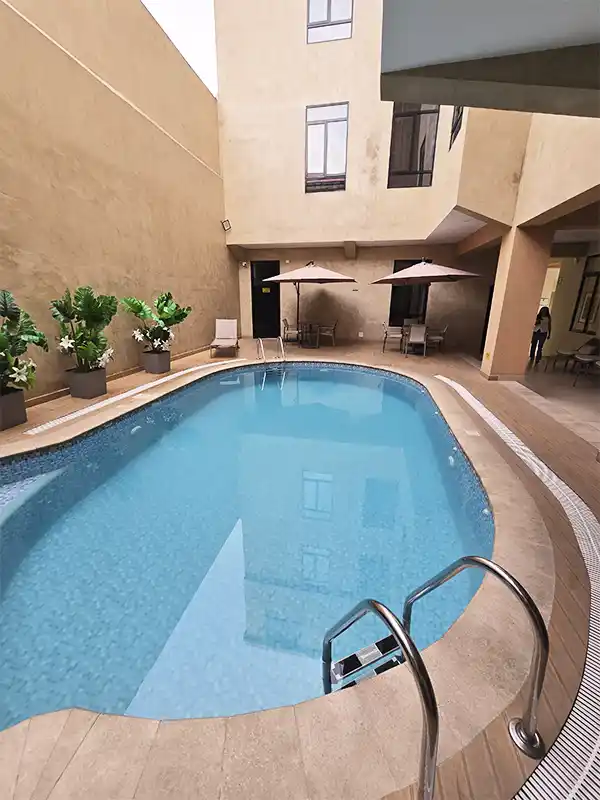 Piscina del hotel en Iquitos, Perú, con reposeras, sombrillas y plantas tropicales alrededor.