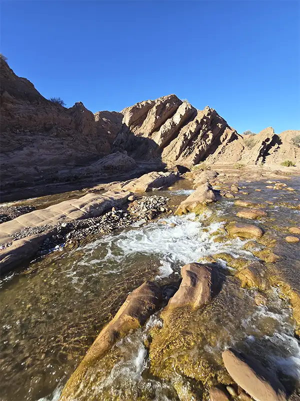 Arroyo de aguas cristalinas entre formaciones rocosas en la Cuesta de Huaco, Jáchal, San Juan