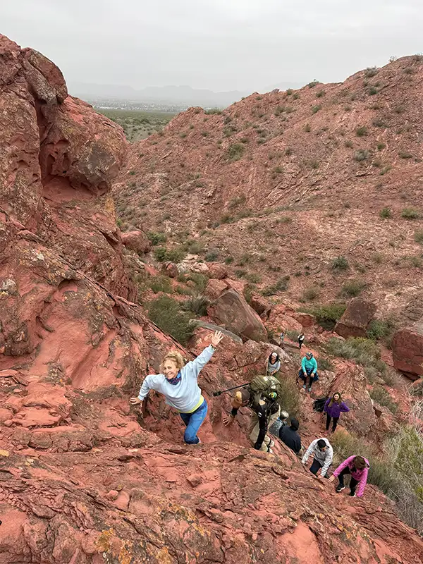 Viajeros ascendiendo entre formaciones rocosas rojizas en Los Coloraditos, San Juan