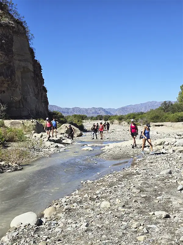 Grupo de trekking cruzando el arroyo durante la excursión a Pasleam, San Juan