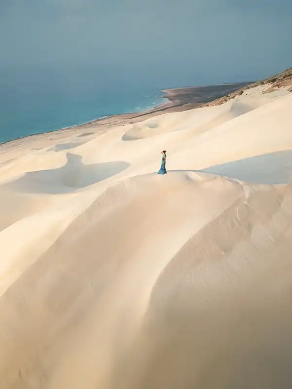 Viajero caminando entre dunas blancas junto al mar en Socotra